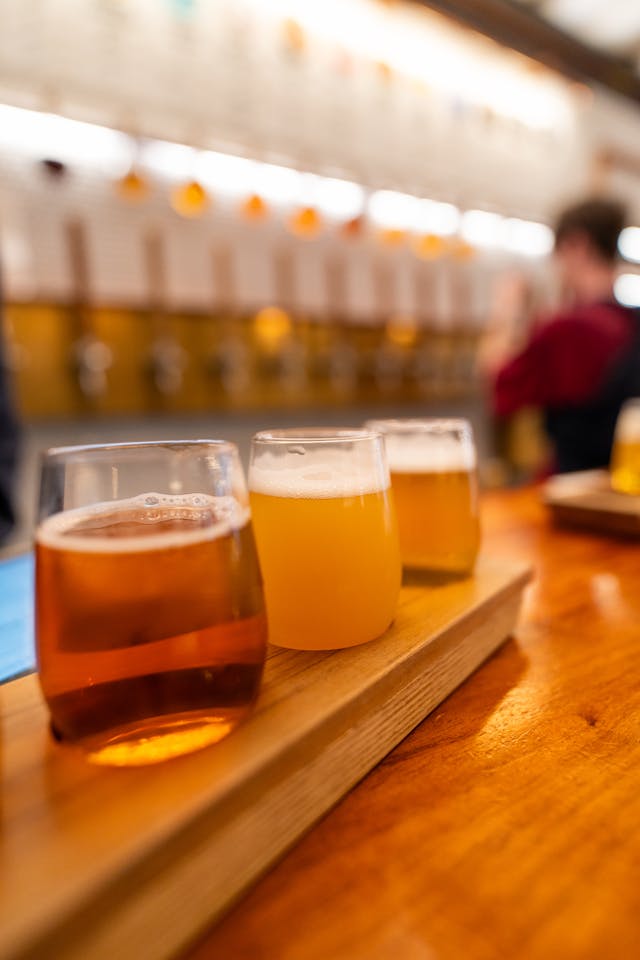 Beer flight with four different craft beers on a wooden paddle at a bar setting